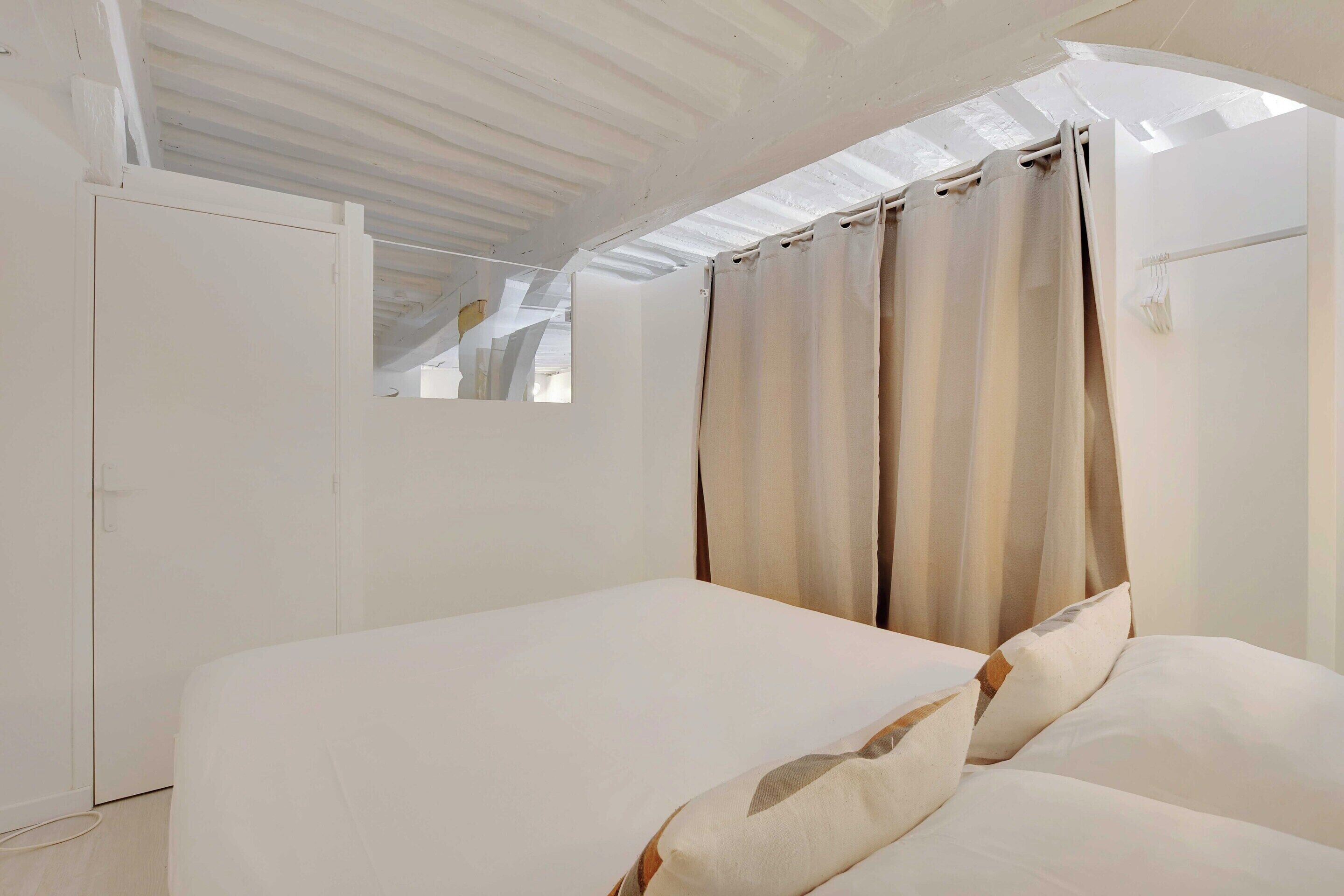 Une chambre à coucher avec un lit, des rideaux et une armoire.