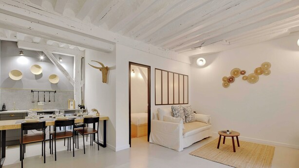 A modern interior with a dining area, a sofa, and decorative wall art. - Elegant Apartment -2br-4p- Le Marais (Paris)