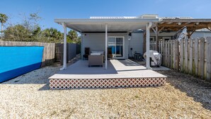 A covered patio with a pool, outdoor seating, and a wooden fence. - Seas the Day, Pet Friendly - Walk to public beach! (Panama City Beach)