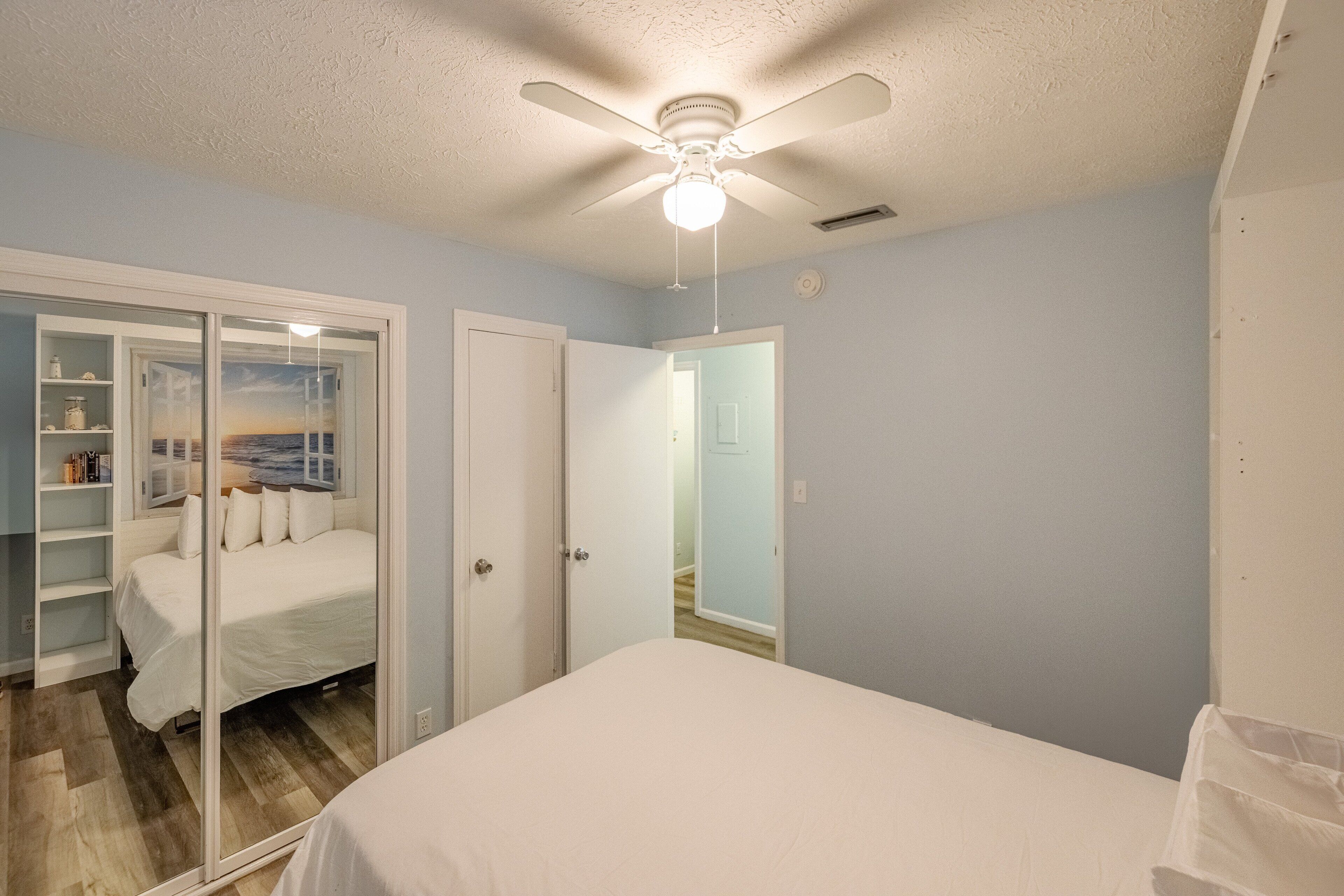 Un dormitorio con cama, ventilador de techo y armario con vistas al exterior.