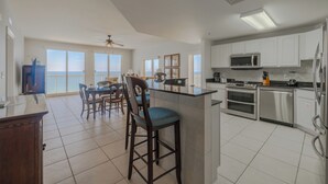 A spacious kitchen with a bar area, large windows, and a view of the ocean.
