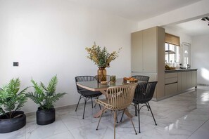 A dining area with a glass table, black chairs, and a vase of flowers.