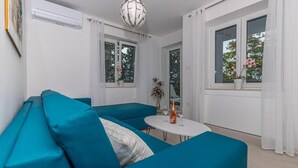 A modern living room with teal sofas, a round white table, and a decorative globe light. - Apartman Maxim (Crikvenica)