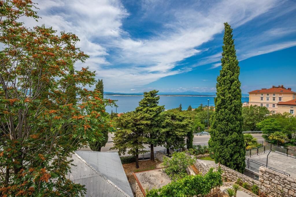 Une vue sur la côte, avec un mur de pierre, des arbres et un bâtiment doté d’un toit rouge.