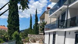 A modern building with a swimming pool, outdoor seating, and a stone wall. - Apartman Maxim (Crikvenica)