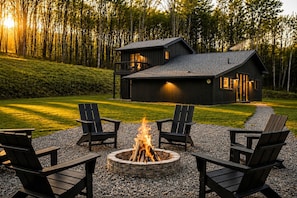 A cabin with a fire pit and outdoor seating, surrounded by a forest. - Hot Tub, Fire Pit, Views & 14 Acres | Onyx Ridge (Jeffersonville)