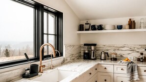 A kitchen with a large window, a sink, a coffee maker, and a marble countertop. - Hot Tub, Fire Pit, Views & 14 Acres | Onyx Ridge (Jeffersonville)