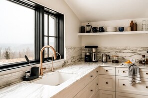 A kitchen with a large window, a sink, a coffee maker, and a marble countertop. - Hot Tub, Fire Pit, Views & 14 Acres | Onyx Ridge (Jeffersonville)