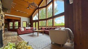 A spacious living room with a wooden ceiling, large windows, and a fireplace. - Grace Woods - Private Lake - Dock -Large Groups - 3 Entire Homes-Lake House (Rising Sun)