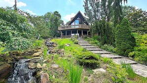 A house with a wooden deck and a waterfall in the foreground. - Grace Woods - Private Lake - Dock -Large Groups - 3 Entire Homes-Lake House (Rising Sun)