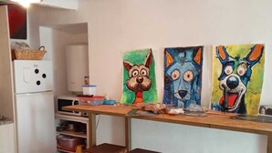 Una cucina con angolo di sgambello in legno, elettrodomestici bianchi e quadri colorati alle pareti.