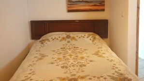 Una camera da letto con un letto, due quadri appesi al muro e una testiera in legno.