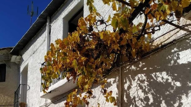 Un edificio bianco con una porta in legno e un piccolo balcone.