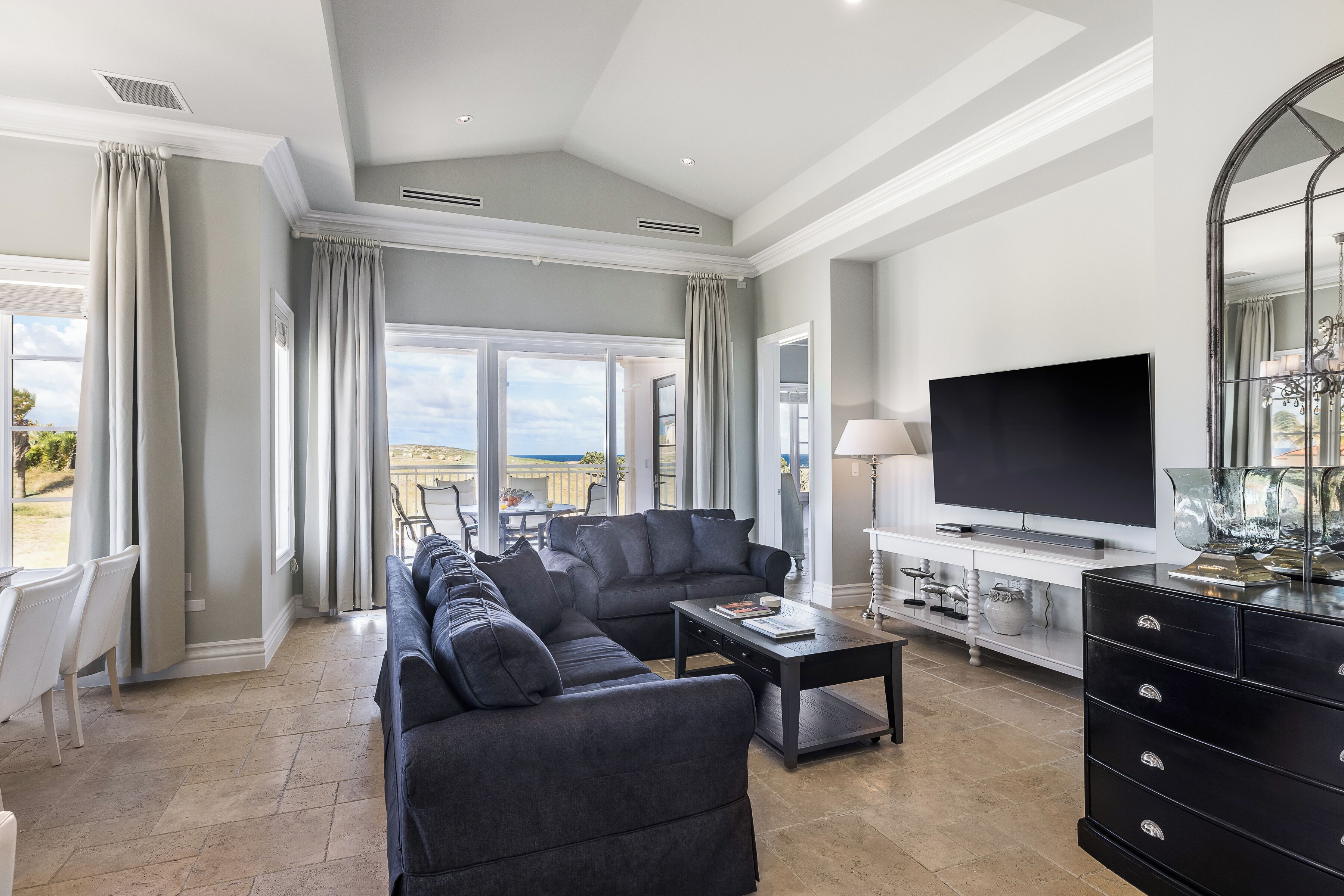 Een moderne woonkamer met een hoekbank, een flatscreen televisie en een eethoek met stoelen.