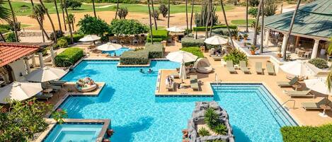 Um resort com uma piscina grande, palmeiras e vista para o oceano.
