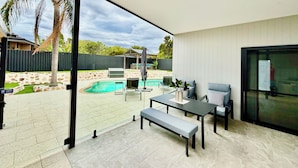 A covered patio area with a pool, outdoor seating, and a view of the backyard. - Joondalup Hidden Villa Gemma w Pool! (Heathridge)