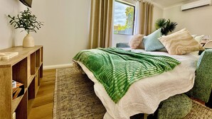 A bedroom with a bed, a bedside table, a window with curtains, and a plant. - Joondalup Hidden Villa Gemma w Pool! (Heathridge)