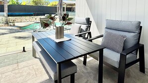 An outdoor patio area with a pool, a wooden table, and two chairs. - Joondalup Hidden Villa Gemma w Pool! (Heathridge)