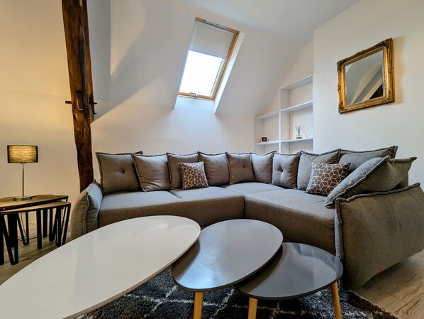 A modern living room with a sectional sofa, two round tables, a lamp, and a skylight. - Modern house with secure pool in La Vernelle (La Vernelle)