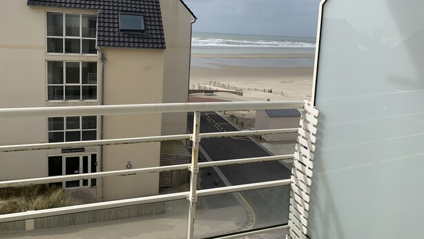 Ein Gebäude mit Blick auf den Strand, ausgestattet mit einem Balkon, einem Geländer, einem Parkplatz und einem Schild mit der Aufschrift 'Residence Les Sables'.