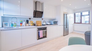 Une cuisine moderne avec des meubles blancs, un four à micro-ondes encastré, un réfrigérateur en acier inoxydable et une fenêtre offrant une belle vue.