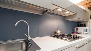 Una cocina moderna con un lavamanos de acero inoxidable, una estufa a gas y armarios blancos.