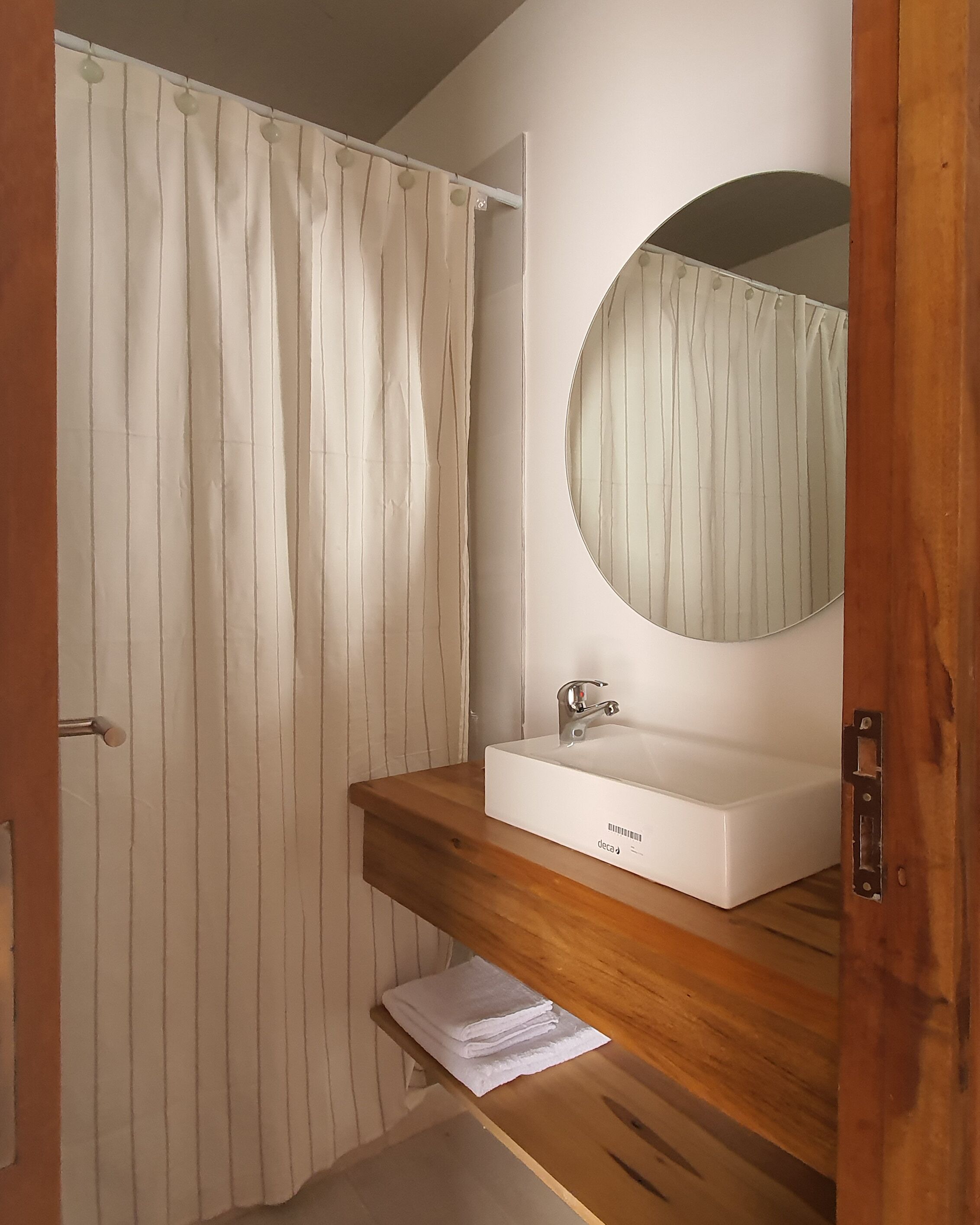Een badkamer met een houten wastafelmeubel, een witte wasbak en een spiegel.