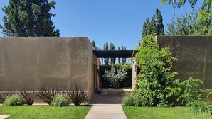 Un chemin menant à un bâtiment doté d’une entrée couverte, entouré de verdure et d’arbres.