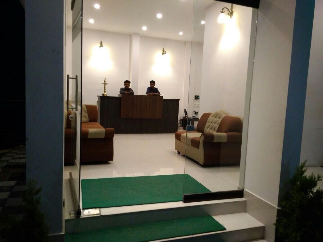A reception area with a reception desk, two sofas, a green carpet, and a staircase.