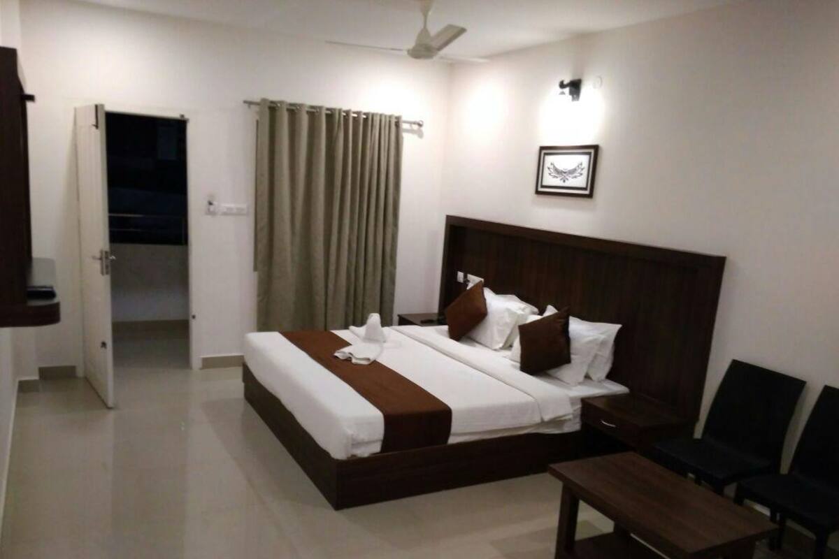 A hotel room with a bed, bedside table, and a chair.