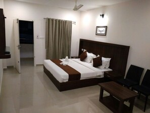 A hotel room with a bed, bedside table, and a chair.