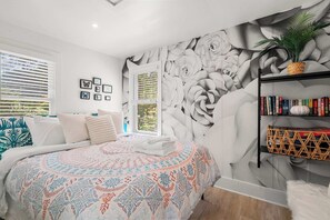 A bedroom with a large bed, a wall mural, a bookshelf, and a window with blinds. - Adorable Updated Cottage, Walk to Water! (Yarmouth)