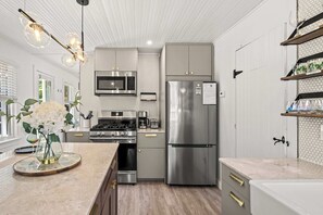 Een moderne keuken met roestvrijstalen apparatuur, een centraal kookeiland en een houten vloer.