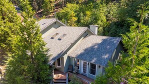A two-story house with a deck, surrounded by dense forest. - Sierra Grand Inside Yosemite (Wawona)