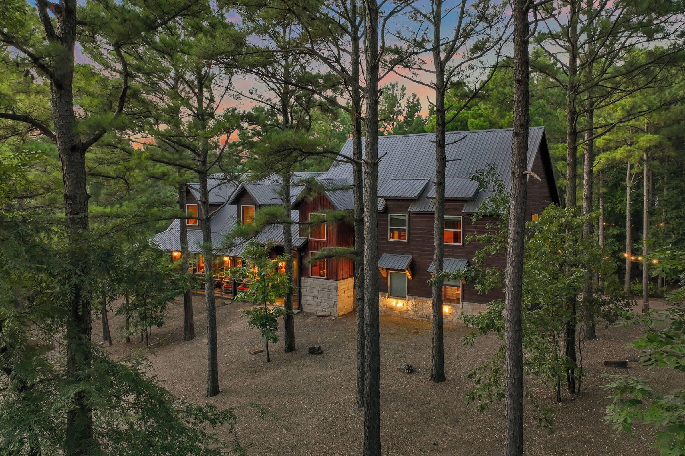 A cabin with multiple rooms, surrounded by trees, and featuring a metal roof.