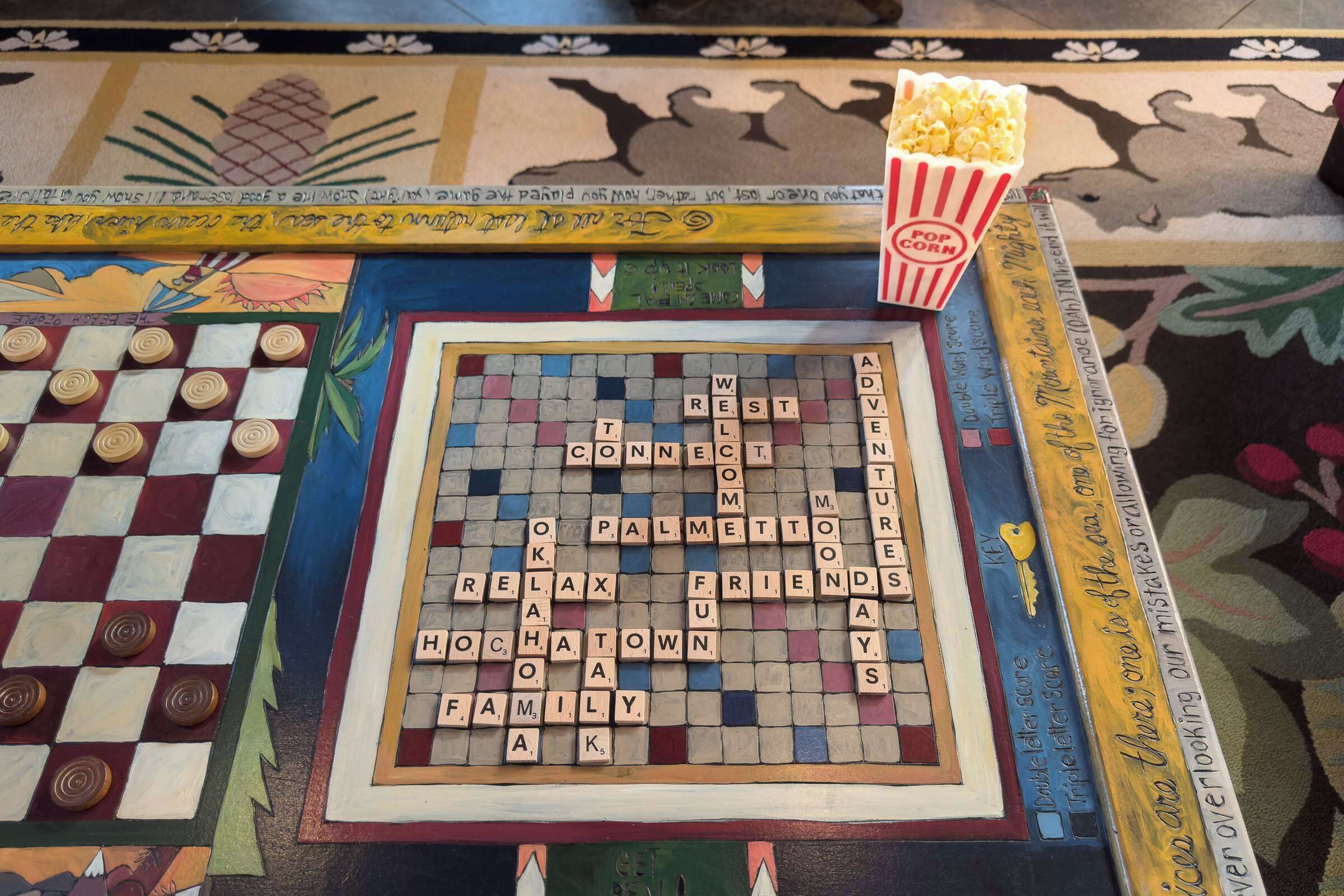 A Scrabble board game with a popcorn bucket beside it.