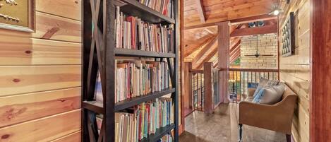 A wooden interior with a bookshelf, a sofa, and a view of the outside.