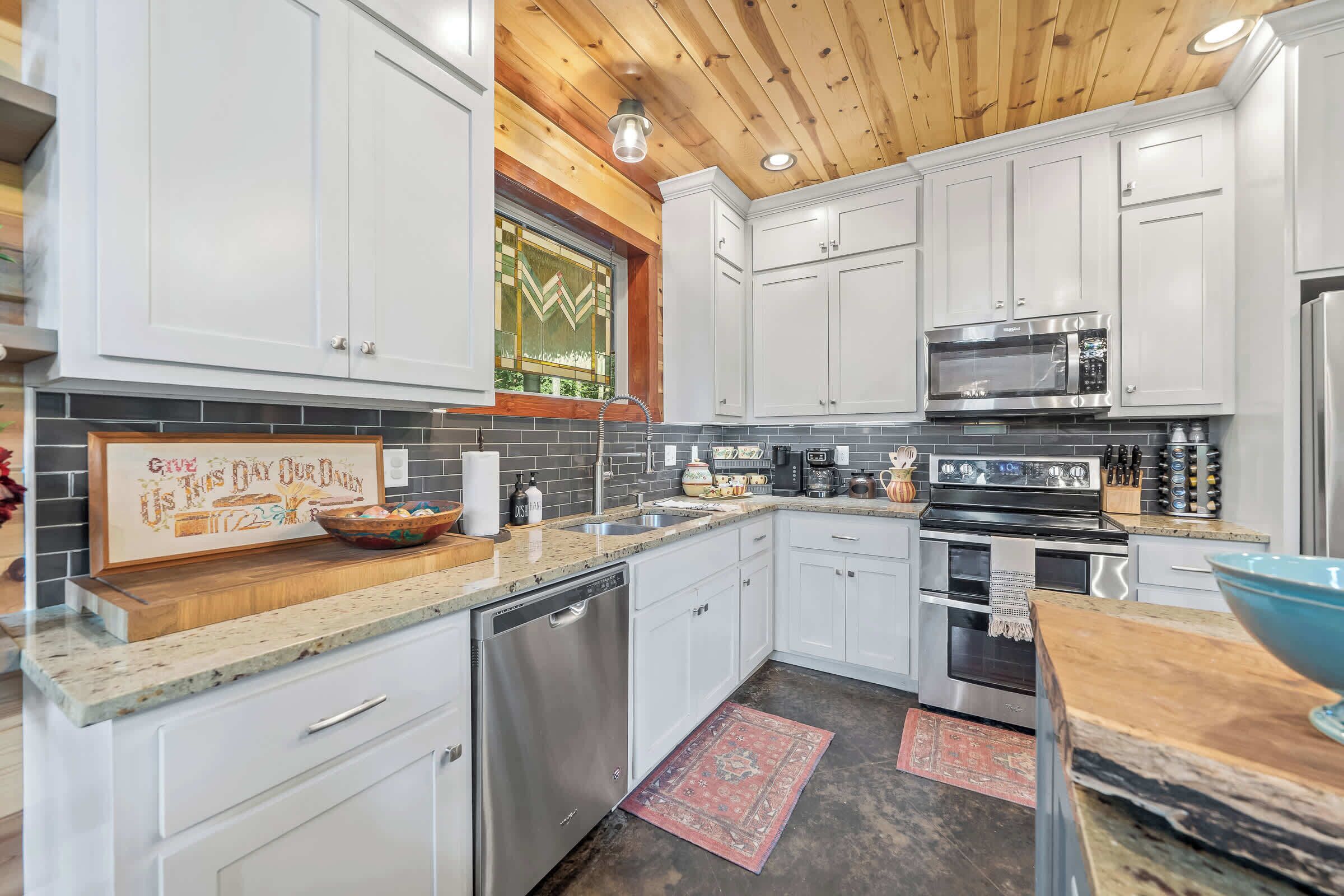 A modern kitchen with white cabinets, a stainless steel microwave, and a dishwasher.