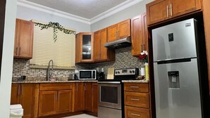 A kitchen with wooden cabinets, a stainless steel refrigerator, a microwave, an oven, and a water dispenser.