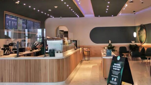 A modern cafe with a wooden counter, seating area, and decorative wall art.