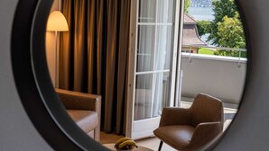 A balcony with a view of a lake and buildings, a lamp, and two chairs. - Seehotel Winkelried (Stansstad)