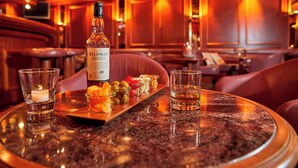 A bar setting with a bottle of Talisker single malt whisky, glasses, and a tray of snacks. - Seehotel Winkelried (Stansstad)