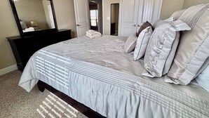 A bedroom with a bed, a dresser, a mirror, and a door. - Raiderland Rest Stop - 3BR/2BA - Close to Campus (Lubbock)