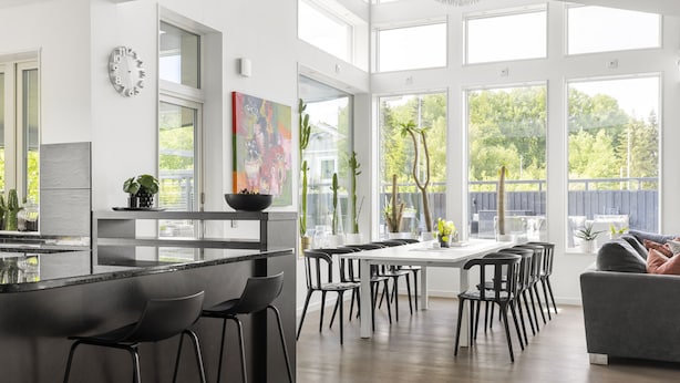 A modern kitchen with a large island, bar stools, and a dining area with multiple chairs.