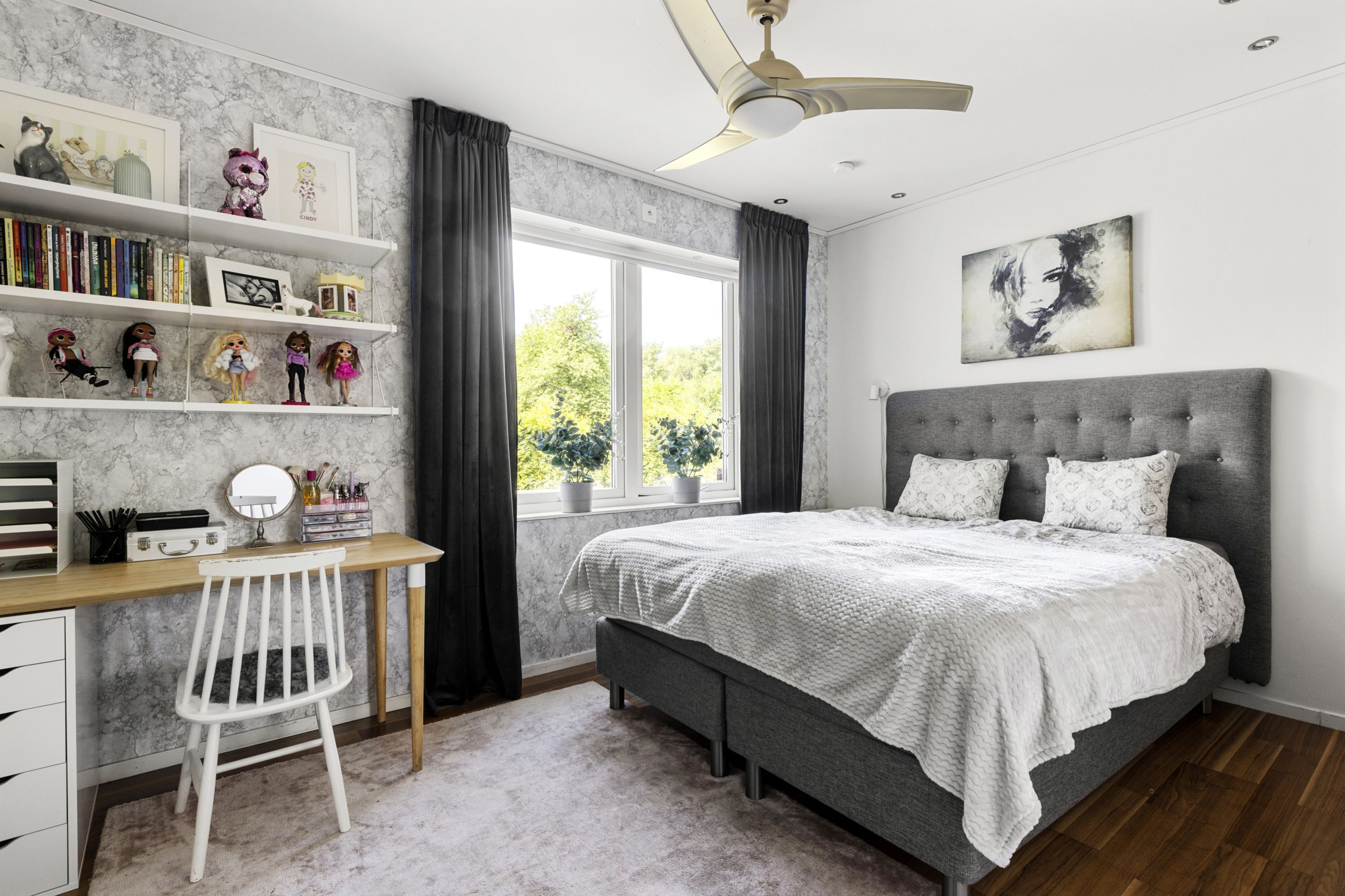 Un dormitorio con cama, escritorio, silla y ventana con cortinas.