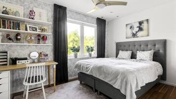 Un dormitorio con cama, escritorio, silla y ventana con cortinas.