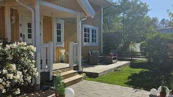 A two-story house with a covered porch, a small garden, and a paved driveway.