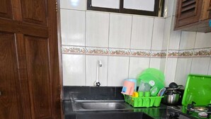 Een keuken met houten kastjes, een zwart aanrecht en een betegelde spatwand.