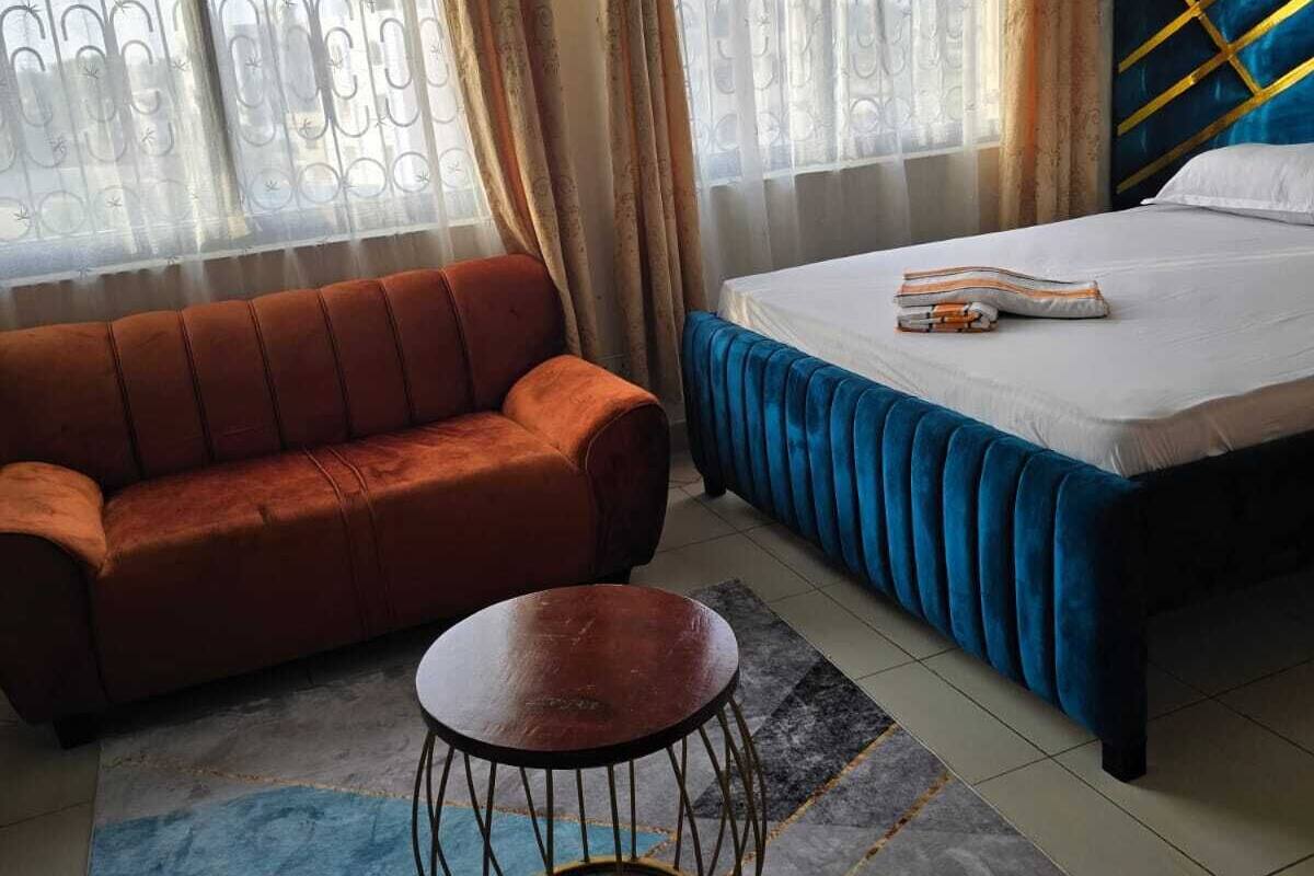 Un dormitorio con una cama, un sofá y una pequeña mesa redonda.