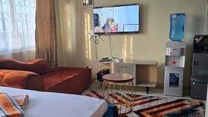 Een hotelkamer met een bed, een televisie, een waterdispenser en een klein tafeltje met een stoel.